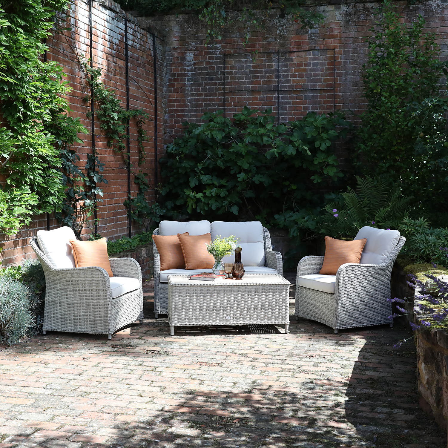 Outdoor patio set with wicker chairs and sofa against a brick wall.