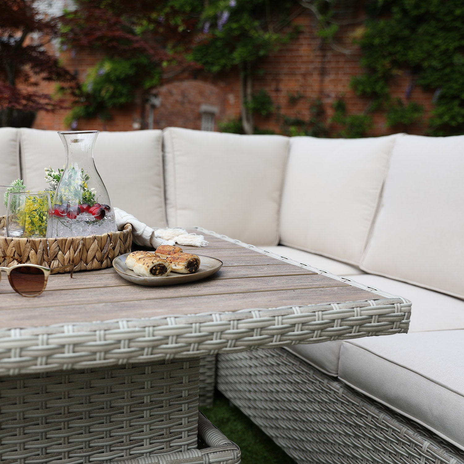 Outdoor patio set with a table and sectional sofa in a garden setting.