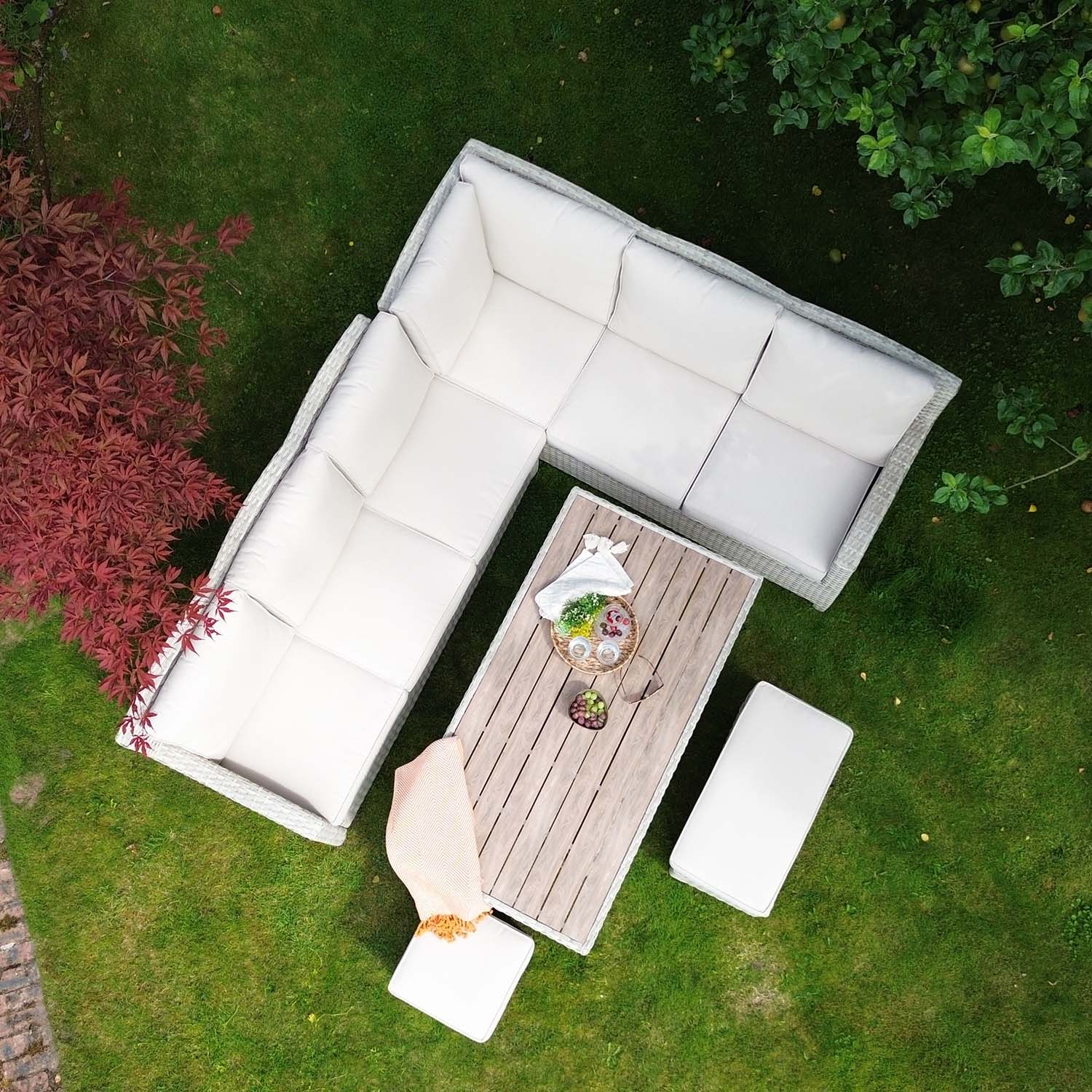 Outdoor patio set with sectional sofa and table on a grassy area