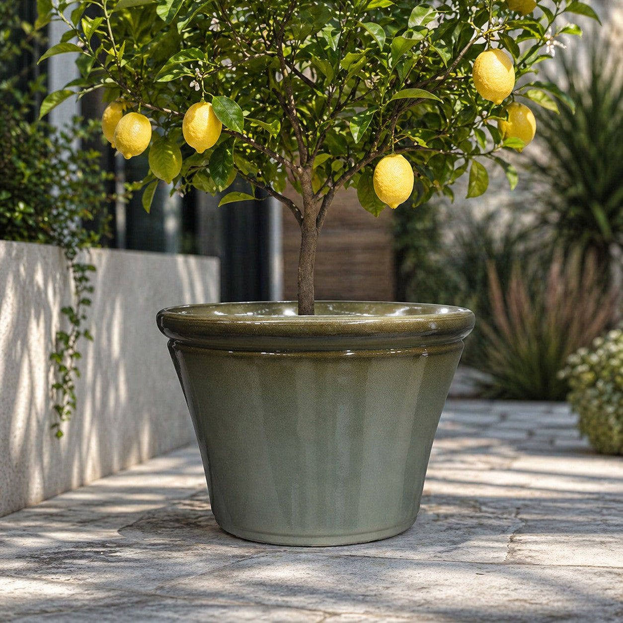 Hortus Lite - Glaze Plastic Rolled Rim Planter - Olive Green- Dia 45cm x Height 29cm lifestyle - fibreglass stone-effect planter with lush greenery on modern garden terrace