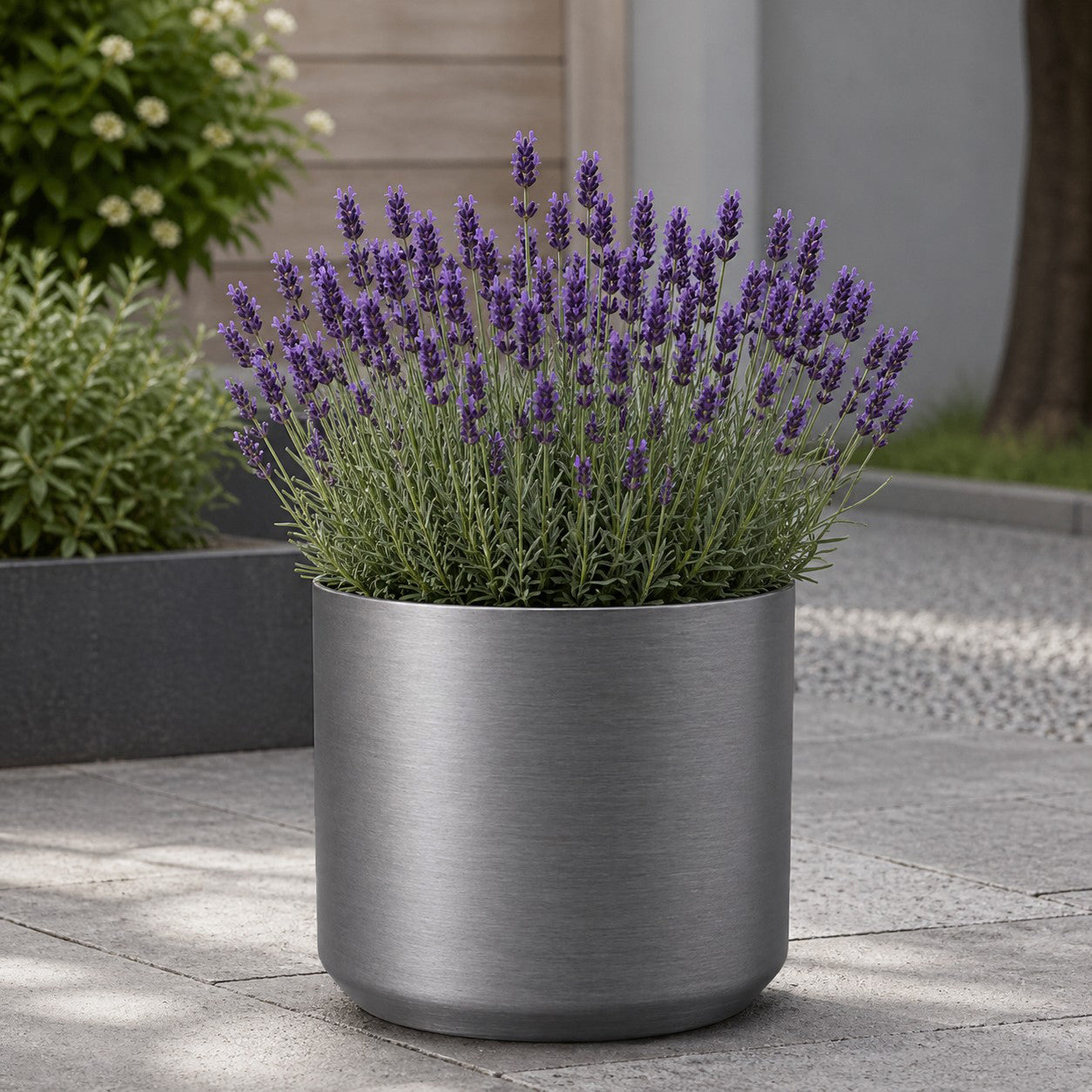 Hortus Lite - Metallic Look Plastic Cylinder Planter - Brushed Steel - Dia35 x H35cm lifestyle - metal cylinder planter with lush greenery on modern garden terrace