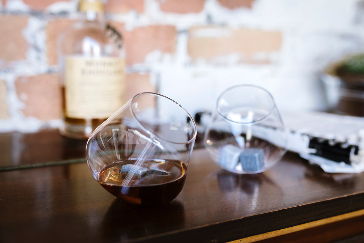 Rocking whiskey glasses resting on a wooden surface
