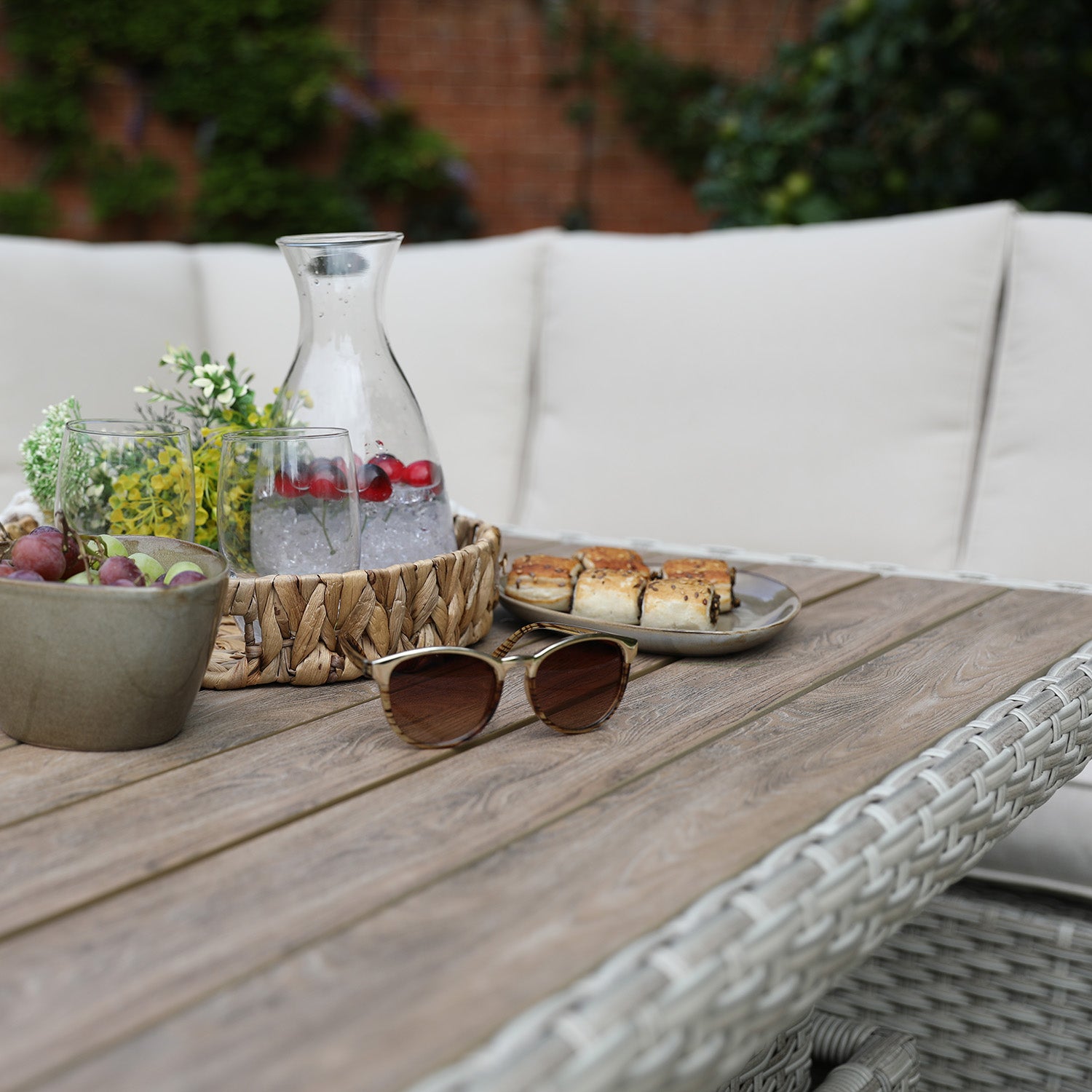 Outdoor setting with a wooden table, sunglasses, and food on a patio.