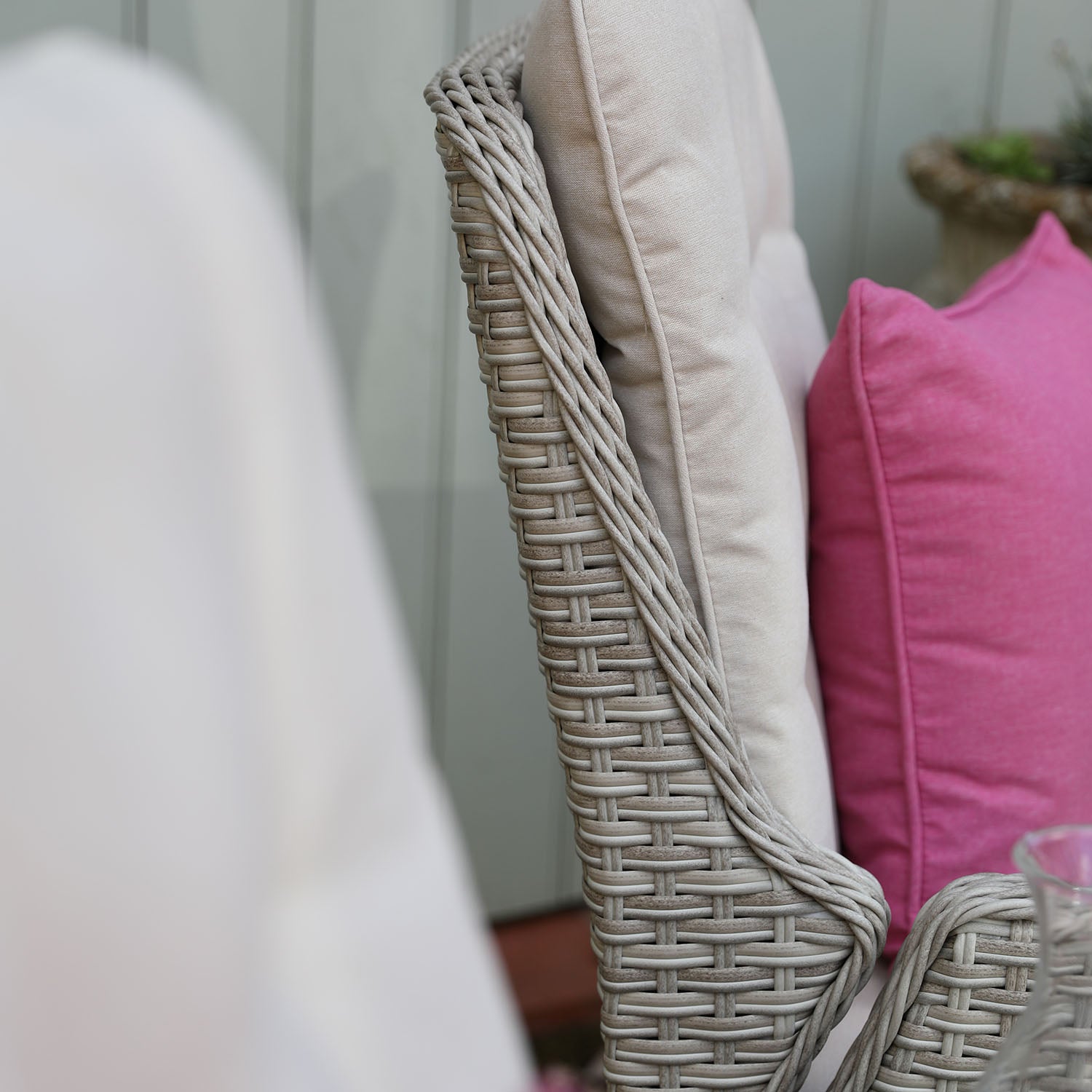 Wicker chair with pink cushion and blurred background