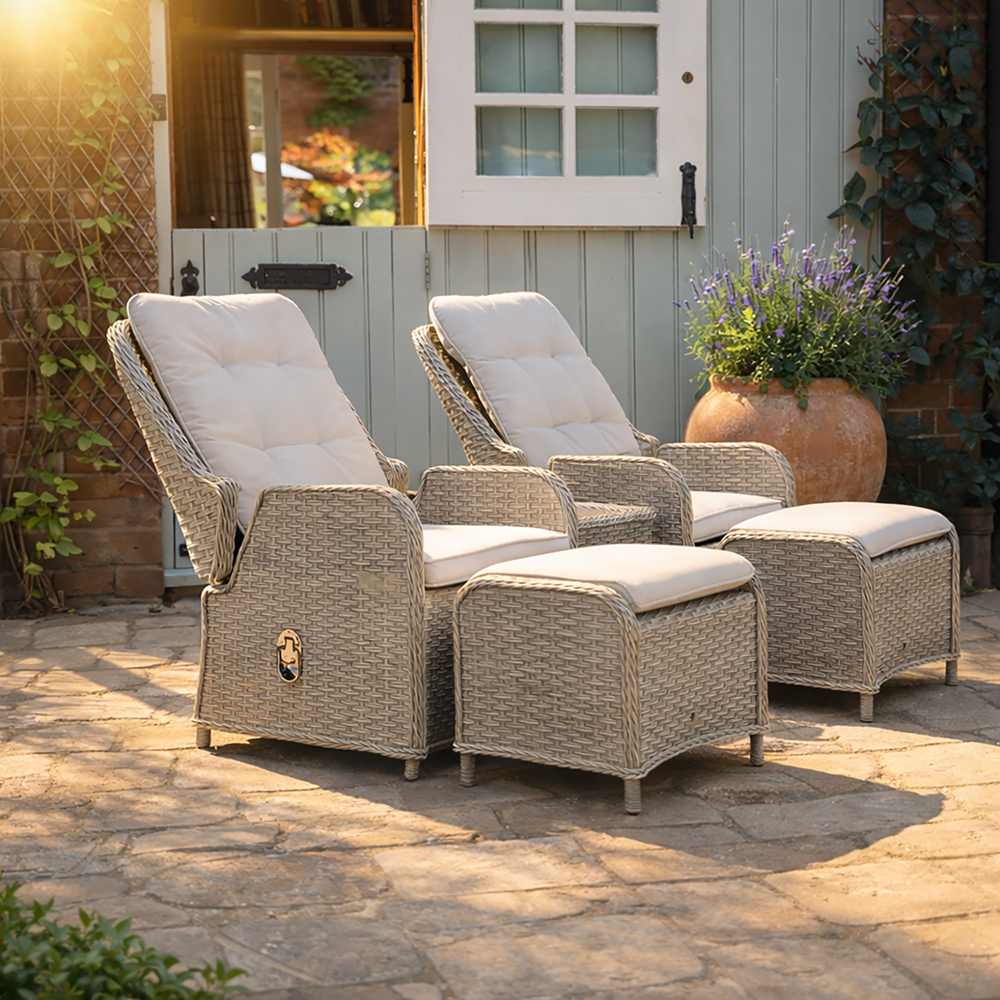 Outdoor patio furniture set with two reclining chairs and ottomans on a stone patio.